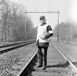 881954 Afbeelding van een veiligheidsman van de N.S. met signaalhoorn, gehoorbeschermers en geel vest op de spoorlijn ...